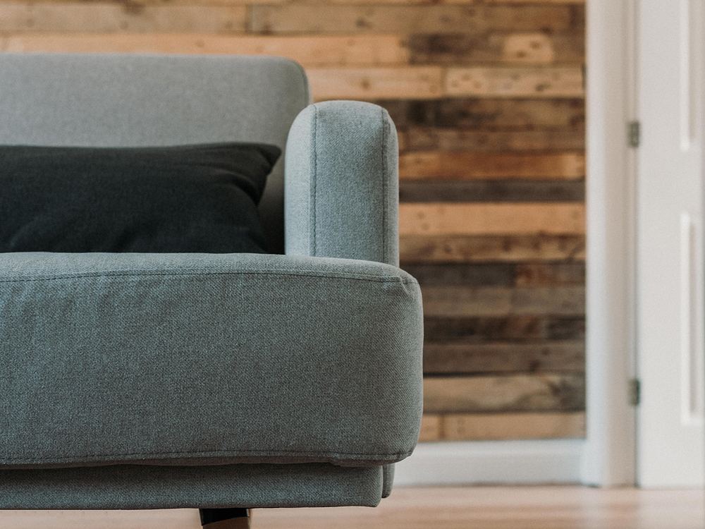 Woonkamer met een wand van houten planken en een fauteuil ervoor